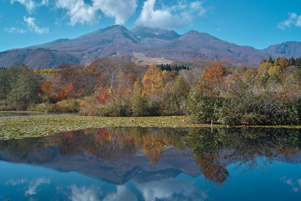 imori pond in autumn with tress showing their colors and blue skies over Mt Myoko